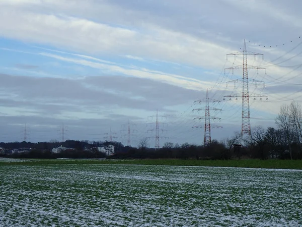 空に雲と雪のフィールド上の電気ネットワークインフラの不気味な風景 — ストック写真