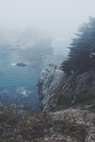 在阴郁的一天 在被雾笼罩的大海包围的岩石悬崖峭壁的垂直拍 — 图库照片