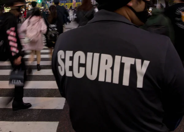 A closeup shot of a security guard in the street of the big city at night