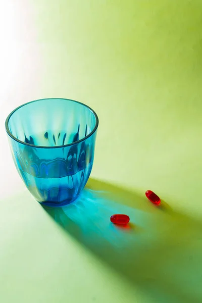 Egy Függőleges Lövés Két Piros Orvosi Tablettával Egy Kék Pohár — Stock Fotó