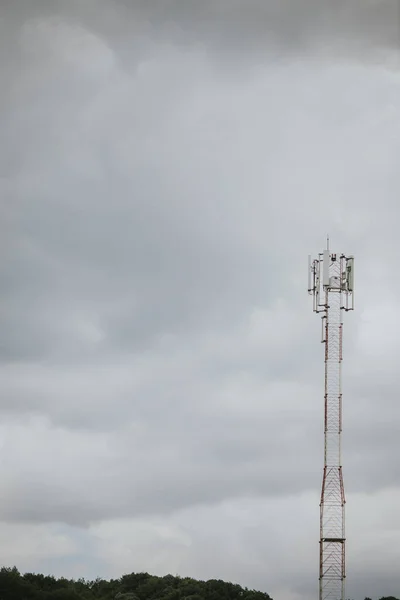 田舎の雲で満たされた暗い灰色の空の下で背の高い通信塔の垂直ショット — ストック写真