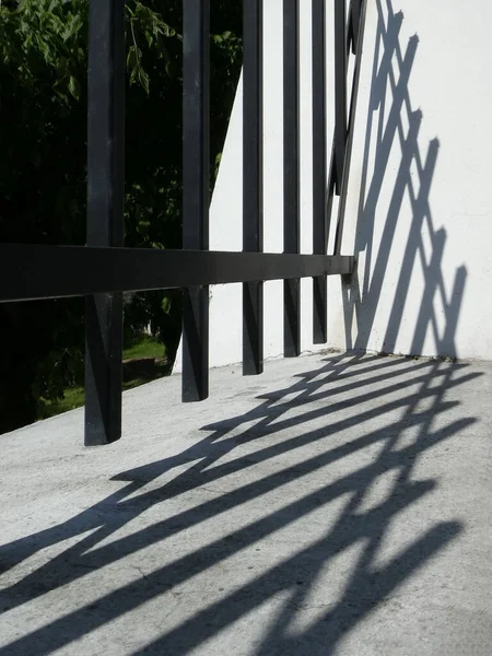 一道铁栅栏的垂直拍和白墙上的阴影 — 图库照片