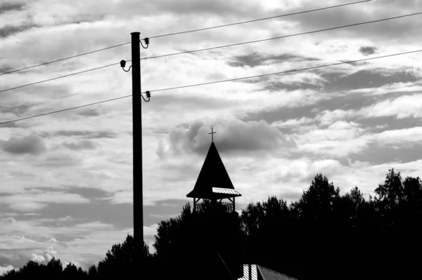 Het Silhouet Van Een Elektriciteitspaal Boomtoppen Kerktoren Tegen Een Bewolkte — Stockfoto