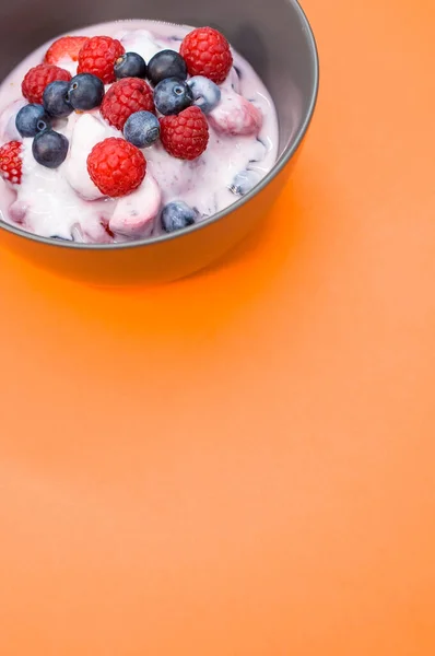 Vertikal Bild Yoghurt Med Hallon Och Blåbär Skål Isolerad Orange — Stockfoto