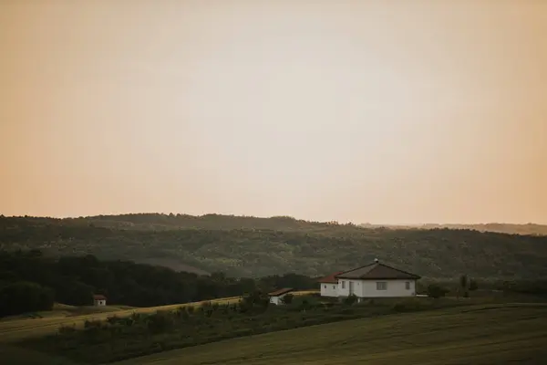 Samotny Dom Bujnym Zielonym Polu Wzgórzami Tle Podczas Złotego Zachodu — Zdjęcie stockowe