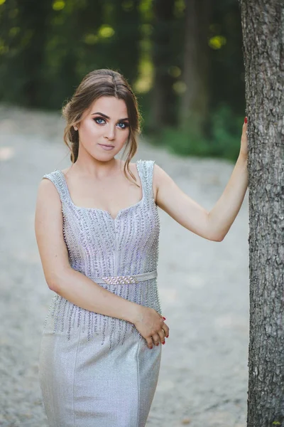 Parktaki Bir Ağaca Yaslanmış Gümüş Bir Elbise Giyen Seksi Sarışın — Stok fotoğraf