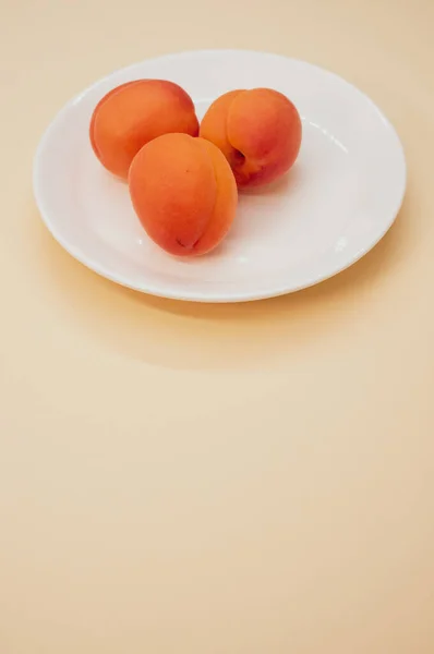 Eine Vertikale Aufnahme Von Frischen Drei Aprikosen Auf Einem Teller — Stockfoto