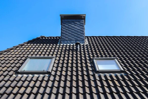 在蓝色天空背景上用黑色瓷砖拍摄的Velux风格的屋顶特写 — 图库照片