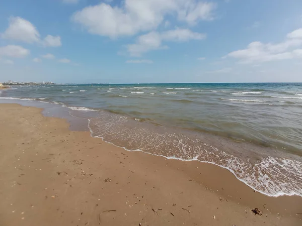 Uma Praia Areia Mar Ondulado Sob Céu Azul Nublado — Fotografia de Stock