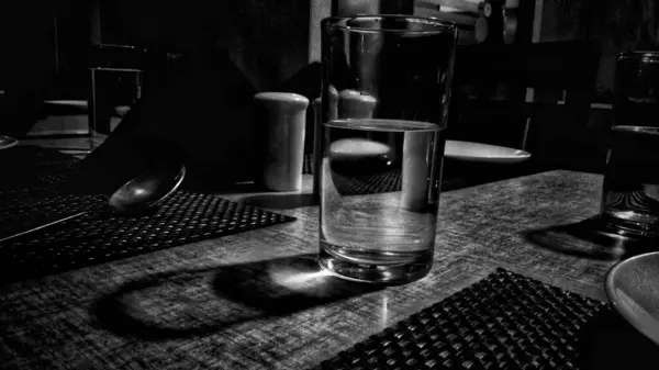 Ett Mjukt Fokus Ett Glas Vatten Ett Matbord Gråskala — Stockfoto