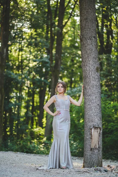 一位漂亮的白人女性 身穿优雅的银色长裙 在公园里摆姿势 — 图库照片