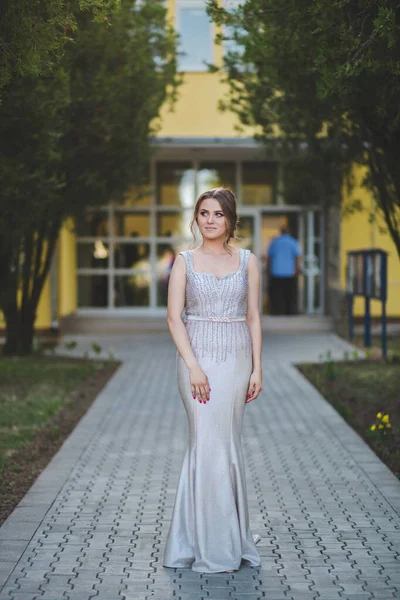 一个漂亮的白人女人穿着银色晚礼服站在酒店大楼前 — 图库照片
