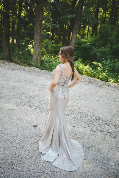 公園に銀のイブニングドレスを着た可愛い白人女性 — ストック写真