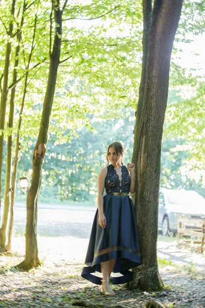 公園でポーズをとっている上品なダークブルーのドレスを着た魅力的な白人女性 — ストック写真