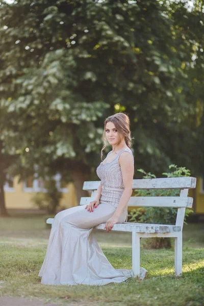 Atraktivní Běloška Elegantních Dlouhých Stříbrných Šatech Sedící Lavičce Parku — Stock fotografie