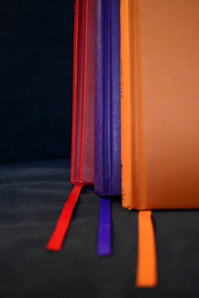 Closeup Three Colorful Hardcover Books Fabric Bookmarks Black Surface — Zdjęcie stockowe
