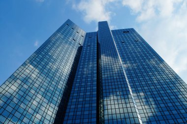 FRANKFURT, GERMANY - Jun 10, 2021: The Deutsche Bank twin towers reflect the blue-white sky and themselves. Also called 'Soll und Haben', means 'Credit and Debit'. clipart