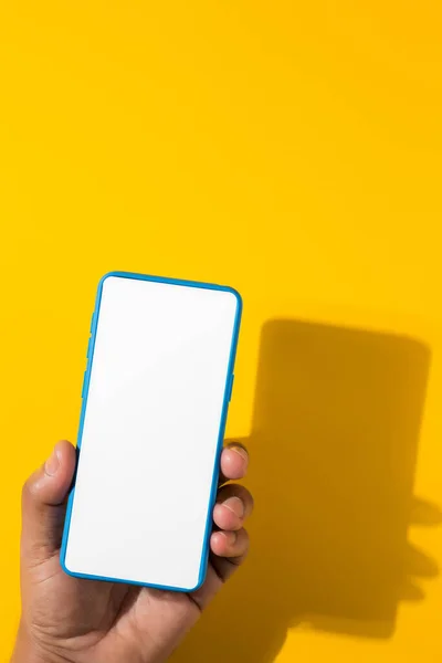 Vertical Shot Hand Holding Blue Smartphone Blank Screen Yellow Background — Φωτογραφία Αρχείου
