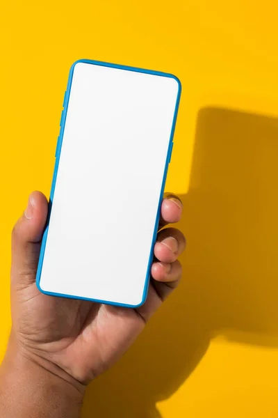 Vertical Shot Hand Holding Blue Smartphone Blank Screen Yellow Background — Stock Photo, Image