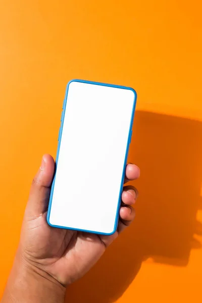 Vertical Shot Hand Holding Blue Smartphone Blank Screen Orange Background — Stock Photo, Image