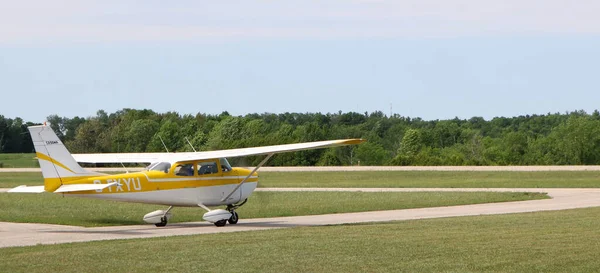 黄色と白の飛行機は晴れた日の朝にカナダのオンタリオ州ハノーバーで離陸するために滑走路に向かって移動します — ストック写真