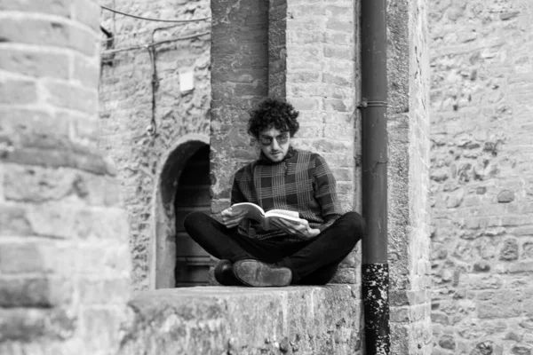 Серый Снимок Молодого Итальянца Сидящего Скрещенных Ногах Читающего Книгу — стоковое фото