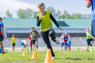 STERLITAMAK, RUSSIA - Jun 15, 2021: A young football goalkeeper performs warm-up exercises. Snake running among the guide cones. Preparing for future victories. Outdoor training. clipart