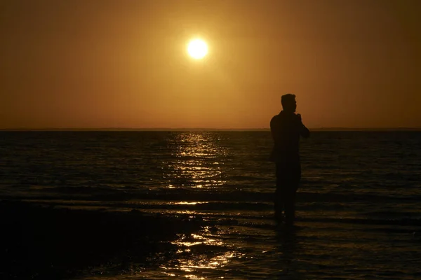 夕暮れ時の浜の人のシルエット — ストック写真