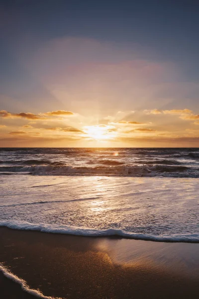 在海洋和沙滩上 一道美丽的落日的垂直拍 — 图库照片