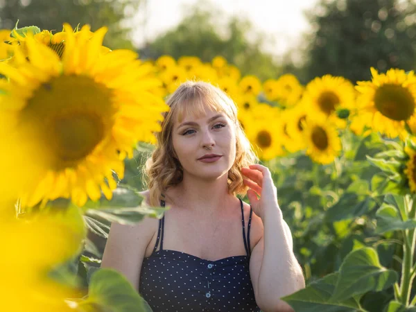 stock image A pretty young lady standing in the sunflower field is looking aw