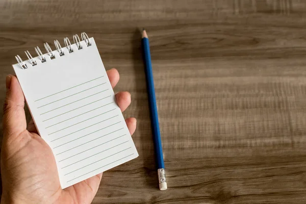 Uma Pessoa Segurando Caderno Contra Uma Mesa Madeira — Fotografia de Stock