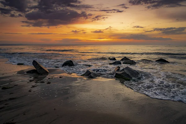 Turuncu Günbatımında Kıyıda Taşlarla Birlikte Nefes Kesici Bir Deniz Manzarası — Stok fotoğraf