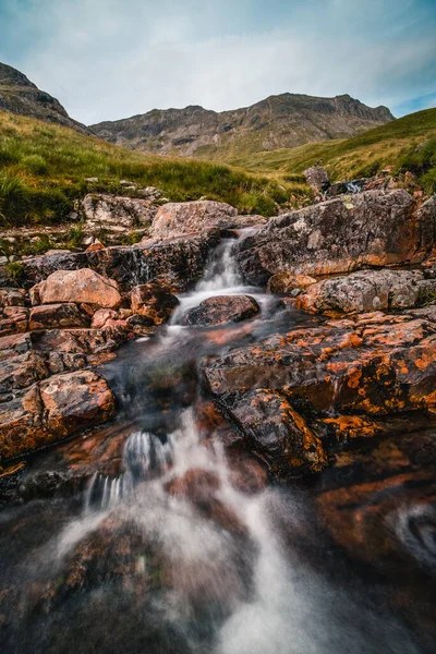 緑に覆われた山の水の流れの垂直ショット — ストック写真
