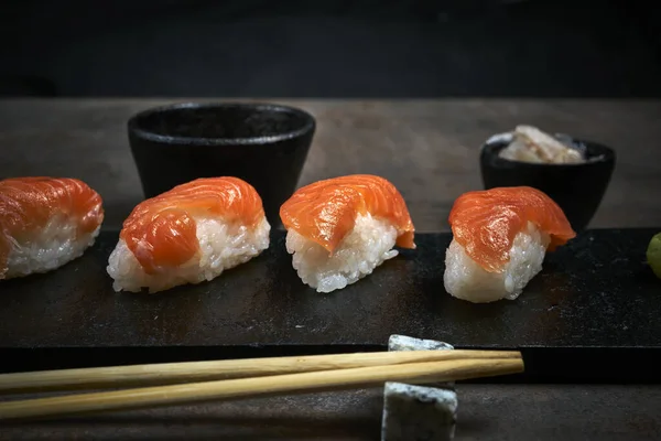 Fotografie Closeup Sushi Placă Neagră Din Lemn Bețișoare Fundal Neclar — Fotografie, imagine de stoc