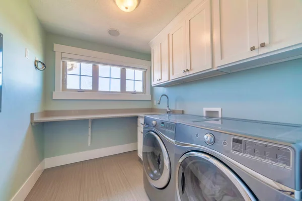 A laundry room with a washing machine, a dryer, and wooden cabinets for clothes