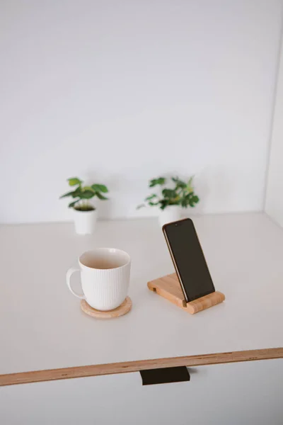 木製の板の上に白いカップと電話のクローズアップショット — ストック写真