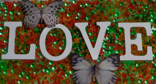 Kelebekler Yeşil Bir Yüzey Üzerindeki Parlak Boncuklarla Aşk Kelimesine Yakın — Stok fotoğraf