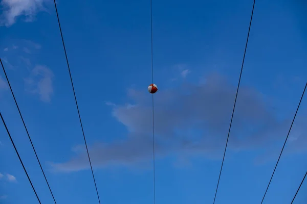 赤と白のボールの低角度ショットは 上を飛ぶコウノトリと高電圧電源ラインからハングします — ストック写真