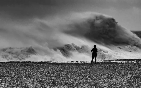 Сірий Знімок Людини Стоїть Узбережжі Біля Хвилястого Моря — стокове фото
