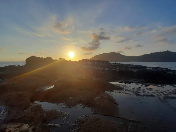 Beautiful sunbeam on extreme terrain from a rocky coast with a rock plateau and water puddles filled from waves at Wediombo beach, Java, Indonesia