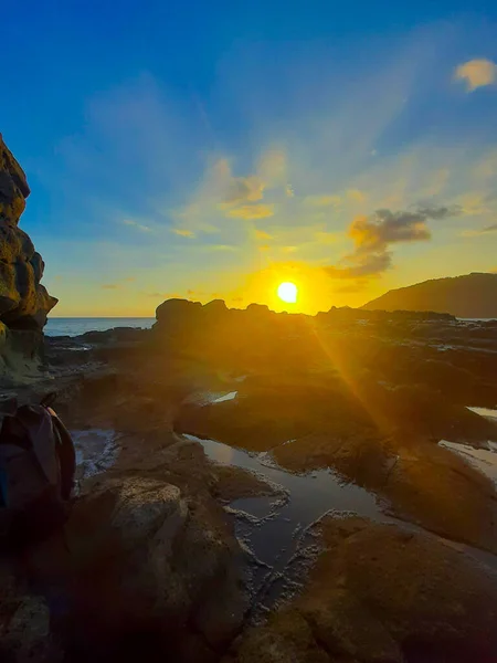 Beautiful sunbeam on extreme terrain from a rocky coast with a rock plateau and water puddles filled from waves at Wediombo beach, Java, Indonesia