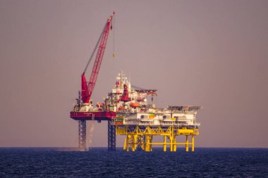A Jackup rig (Fuel Station) in the middle of the ocean captured at twilight clipart
