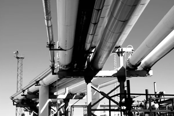 工場の外の澄んだ空の下で大規模な金属パイプの低角度グレースケールショット — ストック写真
