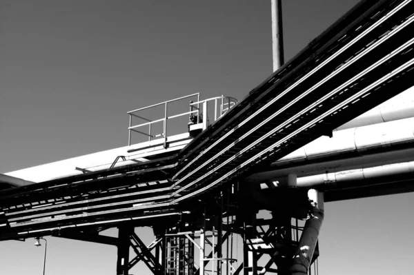 在工业区的晴朗天空下金属框架和金属管结构的灰度照片 — 图库照片