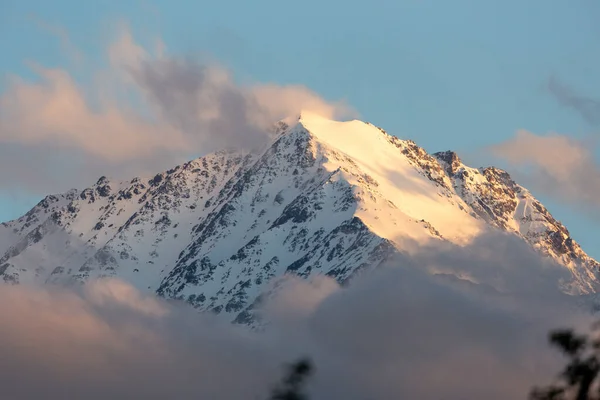 晴れた日に雲を通して見られる雪の中の山の峰の空中ショット — ストック写真