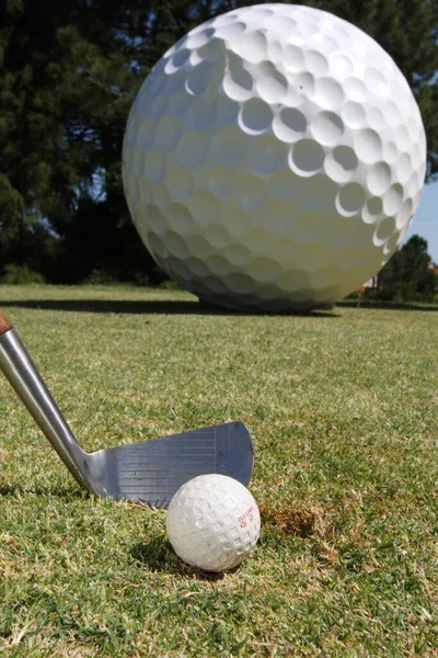 背景に大きなボールのランドマークを持つコース内のゴルフボールとクラブの垂直ショット — ストック写真
