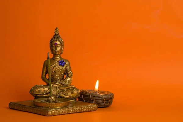 Eine Kleine Buddha Figur Mit Brennender Kerze Auf Orangefarbenem Hintergrund — Stockfoto