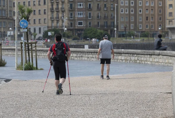 A back view of a sporty person nordic walking by a coast