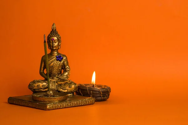 Eine Kleine Buddha Figur Mit Brennender Kerze Auf Orangefarbenem Hintergrund — Stockfoto