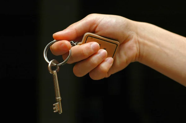 Une Main Tendue Tenant Une Clé Sur Fond Noir — Photo